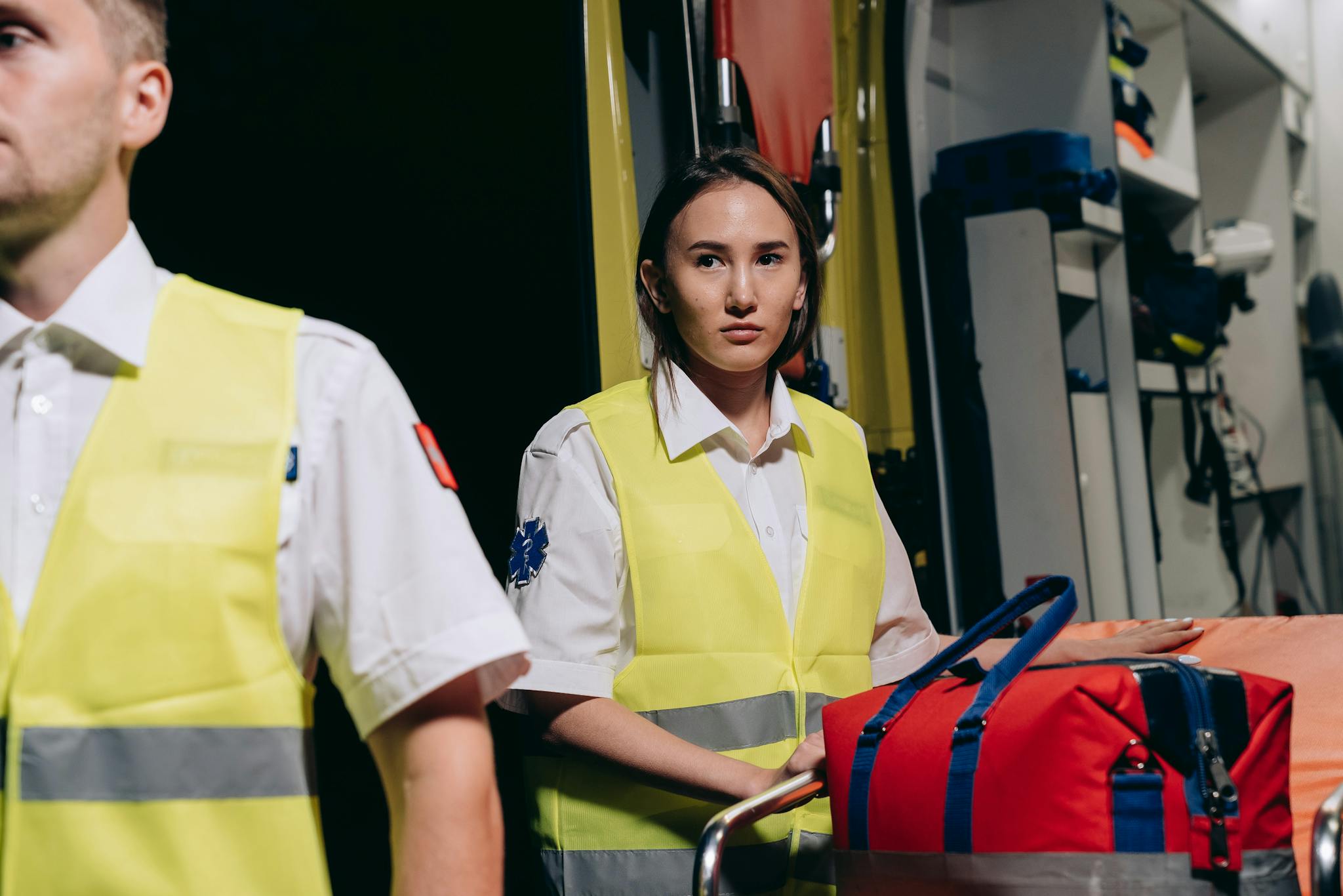 Professional paramedics in reflective vests loading medical equipment into an ambulance for emergency assistance.
